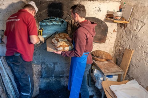 Freshly baked wood-fired bread is taken out of the wood-fired oven, baking oven festival in