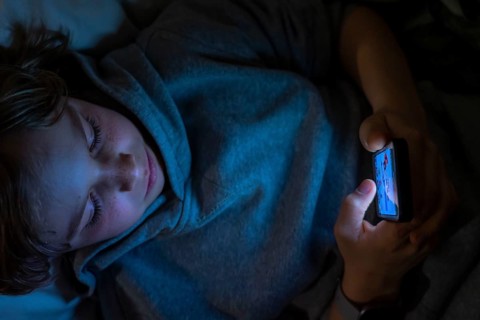 A boy plays computer games on a mobile phone, smartphone