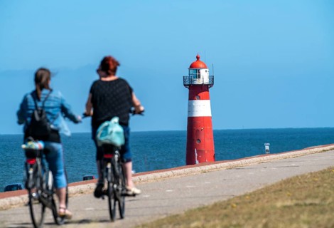 North Sea dyke near Westkapelle, Westkapelle Laag lighthouse, cyclists on the Zeeuwse Wind Route