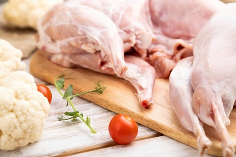 Whole raw rabbit with cauliflower, tomatoes and spices on a white wooden background and linen