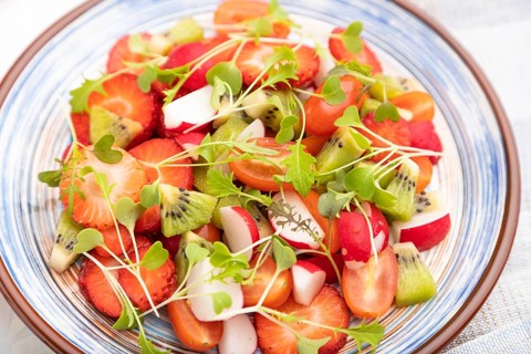 Vegetarian fruits and vegetables salad of strawberry, kiwi, tomatoes, microgreen sprouts on white