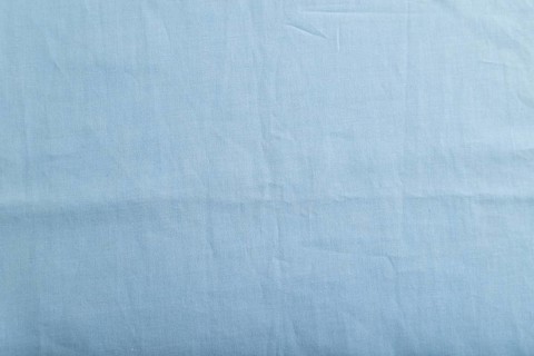 Fragment of smooth cotton blue tissue. Top view, flat lay, natural textile background and texture