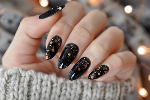 Woman's fingernails with Halloween nail polish art design with golden stars on black base.