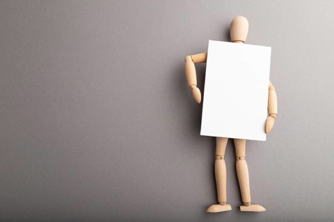 Wooden mannequin holding blank poster on gray pastel background. copy space, isolated, presentation