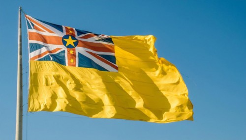 The flag of Niue, an island state in the Pacific Ocean, flutters in the wind, isolated against a