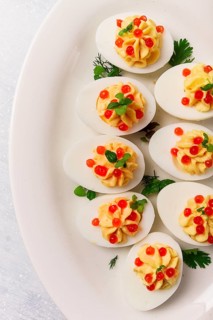 Stuffed eggs, with red caviar, micro greenery, Snack, on a white plate, top view, close-up, no