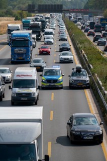 Police patrol car with flashing blue lights and siren working its way through a traffic jam on the