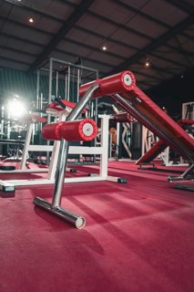 Fitness studio with modern training equipment in red and steel standing on the floor, Historic