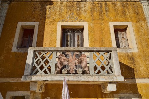 Traditional building with balcony and eagle motif, characterised by yellow colour, Colourful