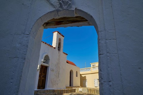 View through an arch of a traditional building against a clear blue sky, Agios Ioannis church,