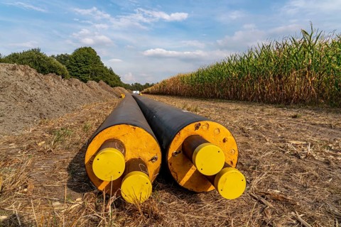 Laying of district heating pipes, next to a field, with maize, the district heating comes from a