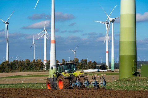 Farmer working in the fields, with a tractor, wind farm above the village of Lichtenau,