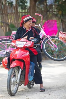 Vietnamese woman in traditional traditional costume from the Dao minority transport a pink bicycle
