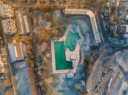 An aerial view of a swimming pool surrounded by streets and trees in winter with frozen water, ENCW