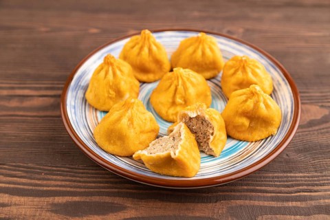 Fried manti dumplings on brown wooden background. Side view, close up