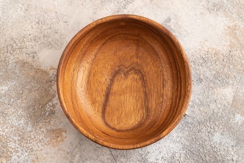 Empty brown wooden bowl on brown concrete background. Top view, copy space, flat lay
