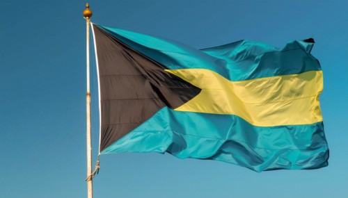 The flag of the Bahamas flutters in the wind, isolated against a blue sky