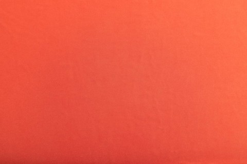Fragment of smooth red silk tissue. Top view, flat lay, natural textile background and texture