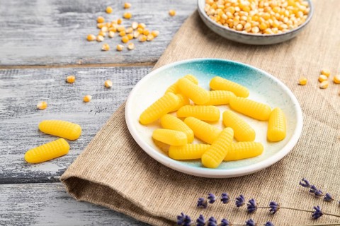 Jelly corn candies on gray wooden background and linen textile. close up, side view
