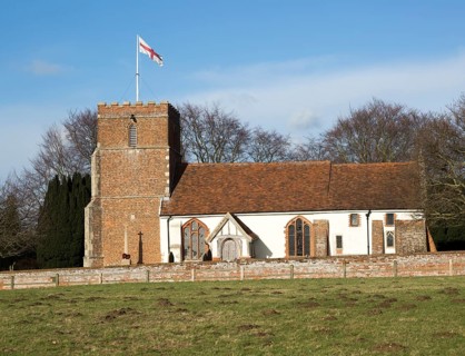 Red cross of flag of St George flying from tower of village Saint Peter church, Levington, Suffolk,