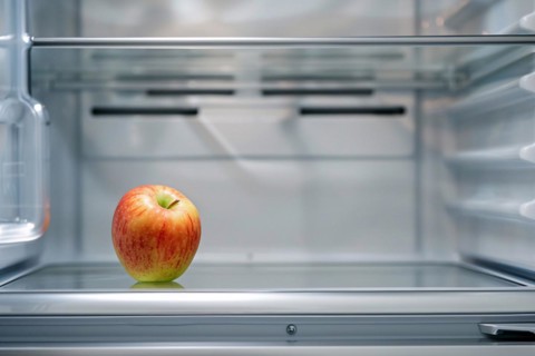 Open refrigerator with only one single apple inside. KI generiert, generiert, AI generated