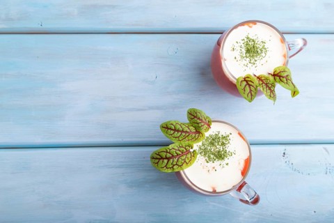 Tomato juice with sorrel and sour cream in glass on blue wooden background. Healthy drink concept.