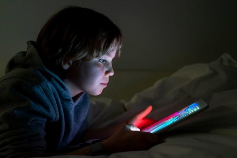 A boy plays computer games on a tablet PC