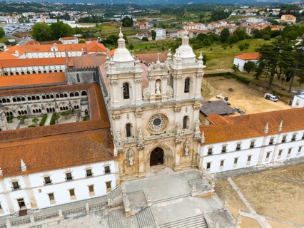 The picture shows a historic monastery with baroque architecture in an urban landscape, aerial