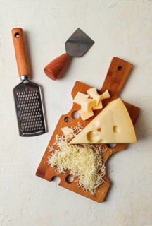Grated cheese, Maasdam, on a cutting board, grater and cheese knife, close-up, no people