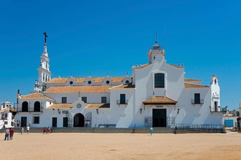 Eine weiße Kirche mit typischer spanischer Architektur vor einem klaren blauen Himmel und