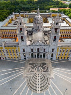 Aerial perspective of a baroque palace with high towers and a large, symmetrical square with a