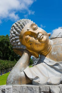 Close-up of a reclining Buddha statue radiating meditative calm against a clear blue sky, Bacalhôa,
