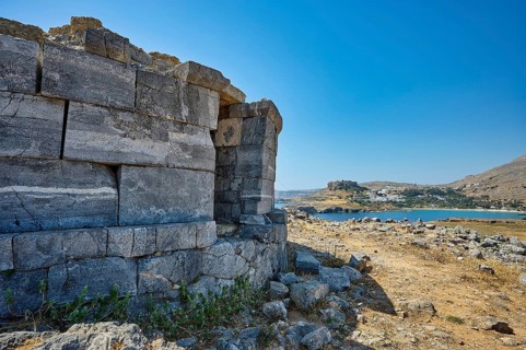 Ruin of an old stone tower with a view of the rocky coast and the blue water in the distance, tomb