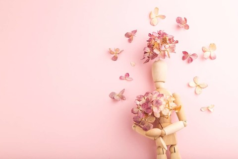Wooden mannequin holding hydrangea flowers on pink pastel background. copy space, isolated, spring,