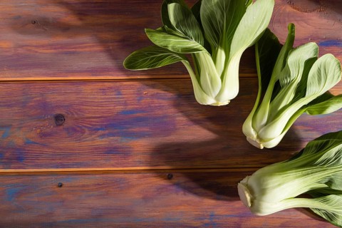 Fresh green bok choy or pac choi chinese cabbage on a colored wooden background. Hard light,