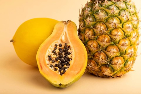 Ripe cut papaya, pineapple, melon, on orange pastel background. Side view, close up. Tropical,