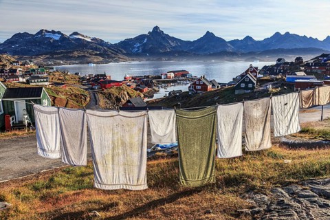 Laundry drying on clothesline in Inuit settlement, houses on a fjord with steep mountains, autumn,