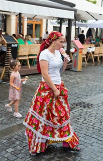 Woman in traditional dress eating ice cream on a busy street, child in the background, young woman