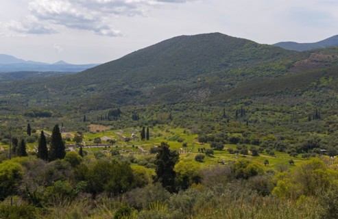 A peaceful landscape with green mountains, trees, farmland and a cloudy sky, view of Messene,