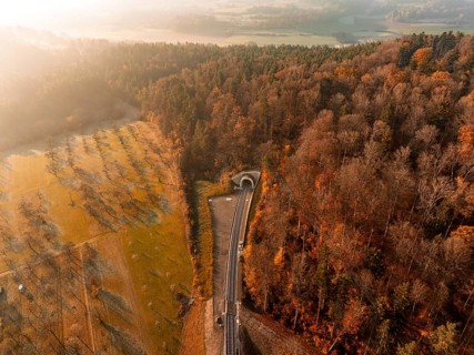 Autumnal aerial view of a forest crossed by tracks and a tunnel in soft sunlight, Weil der Stadt.