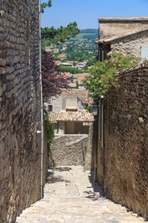 Stony alley in a village with views of houses and countryside in the distance, Vaison-la-Romaine,