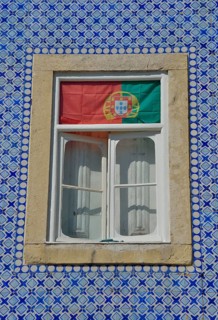 House facade with azulejos wall tiles and the Portuguese flag in the window, historic city