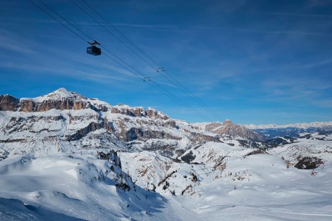 View of a ski resort piste with people skiing in Dolomites in Italy with cable car ski lift. Ski
