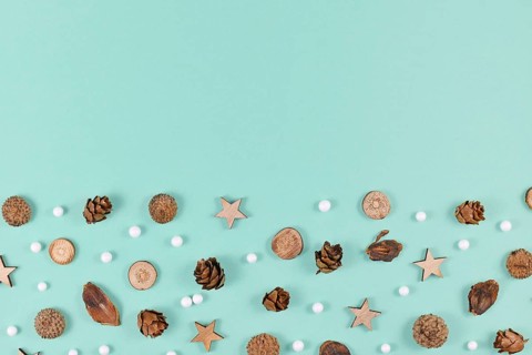 Seasonal decoration like wood slices and cones and Christmas star and snowball ornaments on mint