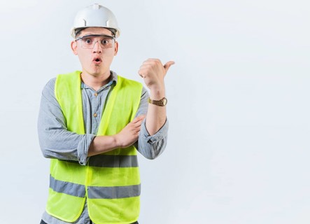 Portrait of surprised engineer man pointing side. Amazed engineer pointing advertising to side