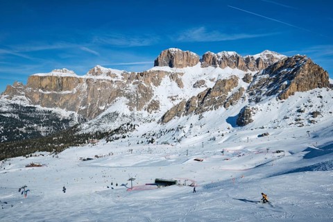View of a ski resort piste with people skiing in Dolomites in Italy. Ski area Belvedere. Canazei,