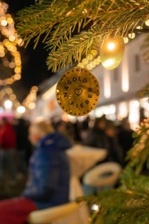 A decorative pendant on a fir branch at a busy Christmas market at night, Christmas market, Nagold,