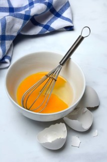 Whipped egg in shell with whisk, egg shells