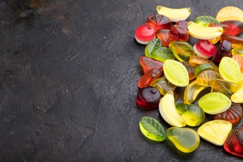 Various fruit jelly candies on black concrete background. side view, copy space