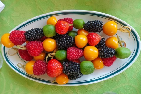 Fruit skewers arranged on serving platter, raspberries, blackberries, kiwi, physalis, bladder